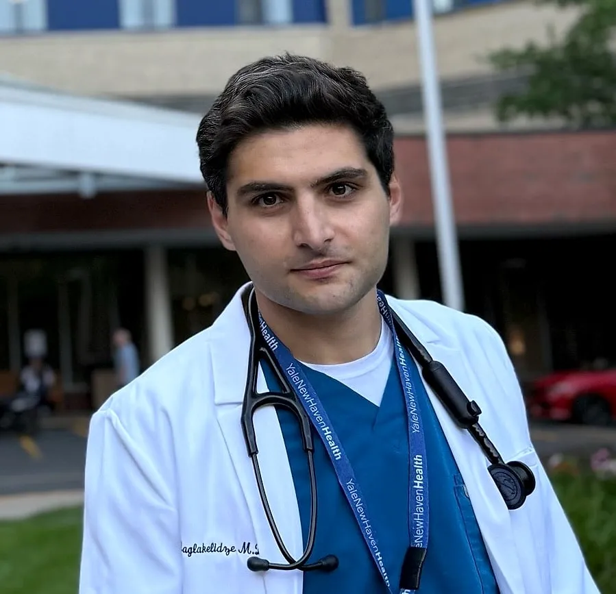 David Maglakelidze, MD, in a white coat and stethoscope outside Yale New Haven Hospital
